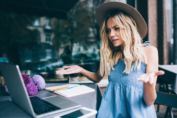 Fototapeta premium Serious female freelancer watching video on laptop computer puzzled on received email message, unhappy hipster girl using netbook device for browsing websites while doing deadline distance job