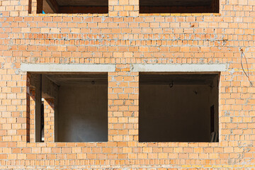 Construction of a red brick multi-storey building. Window openings in a house under construction....