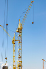 The work of tower cranes against the background of the sunset sky. Modern housing construction. Industrial engineering. Construction of mortgage housing.
