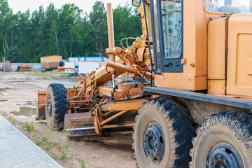 Fototapeta na wymiar Road grader - heavy equipment for road construction and earthworks. Leveling and improvement of the ground surface. Construction of roads and transport communications.