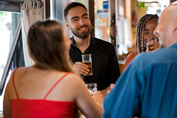 Group of friends enjoying drinking beer together at a bar.