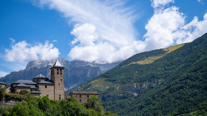 Fototapeta na wymiar Hermosa vista de la Iglesia de Torla con grandes montañas y verdes colinas en Ordesa, España