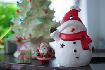 Cute snowman and santa claus as Christmas decoration with a tree in background