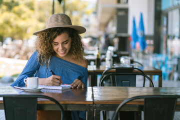 Woman writing on a notebook at a coffee shop.