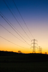 A winter sunset behind electricity power lines and pylons at Milton near Brampton, Cumbria UK