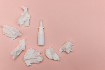 white bottle of nasal spray and crumpled napkins on a light pastel background. The concept of colds, runny nose, allergies. Copy space