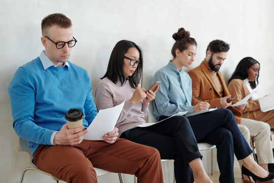 Several young applicants sitting along wall while waiting for their turn for interview