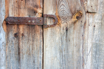 Rusty old door hinge. Rusty hinge on an old wooden fence. Destroyed by the weather and weathered old planks. Flat lay, general plan.