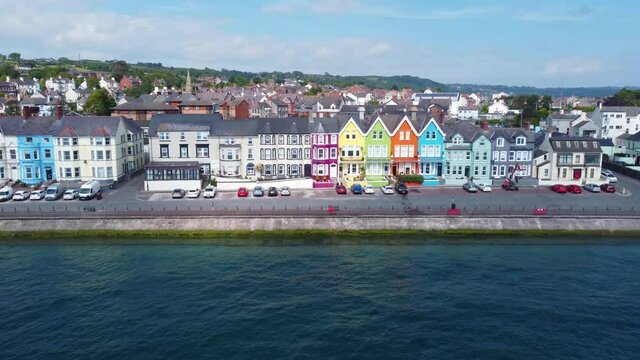 Aerial video of Yellow Red Blue Green Orange painted houses by the sea Whitehead N. Ireland
