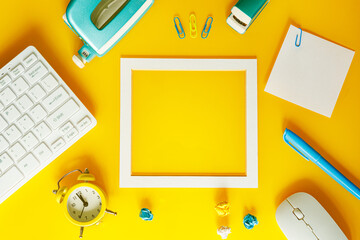 A creative layout of office equipment with a frame in the middle for a note, Yellow, white and blue colors