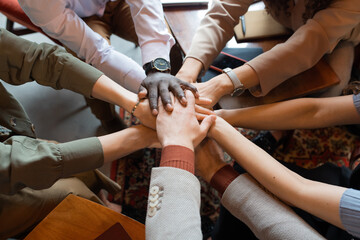 Obraz premium Arms of multiracial colleagues making pile of hands as symbol of companionship