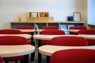 Lecture room with crescent-shaped desks and red chairs. Empty modern classroom. Adult education center. Andragogy.