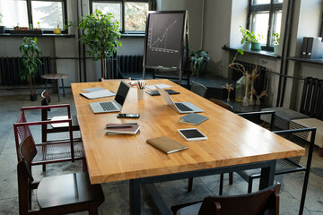 Large table with business objects and group of chairs around it in classroom