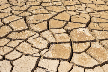 A dry, lifeless, barren clay land cracked in the African desert during global warming and climate change. A hot surface during drought is destroyed, eroded and textured. Copy space, background.