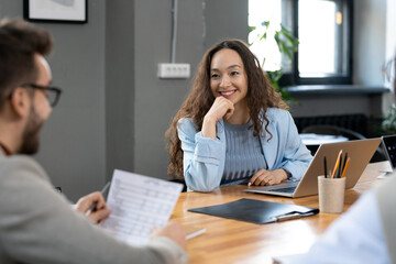 Happy young businesswoman listening to male speaker at seminar
