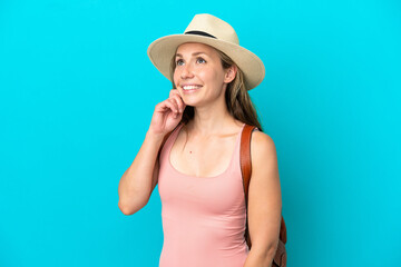 Fototapeta premium Young caucasian woman in summer holidays isolated on blue background thinking an idea while looking up