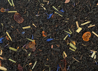 Black tea scented with fruits and flowers, top view. Dried black tea as background.