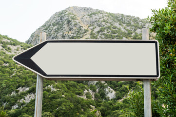 Road blank sign with arrow against mountains.