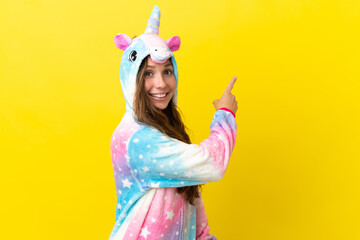 Girl with unicorn pajamas over isolated background pointing back