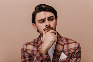 Cute young gentleman with brunette hair and bristle thinking, solving something and looking at copy...