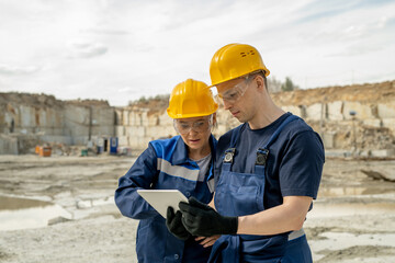 Two colleagues in workwear discussing sketch of new construction at building area