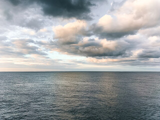 Still image of the ocean before sunset with calm waters and light clouds