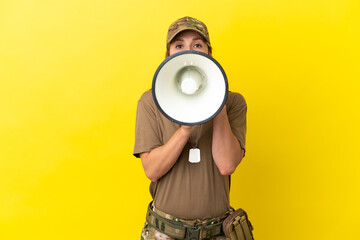 Military caucasian woman with dog tag isolated on yellow background shouting through a megaphone