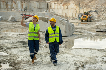 Mature female miner pointing at one of building places while talking to colleague