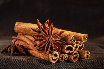 Christmas baking spices, cinnamon sticks and anise stars for Christmas cake, cookies or mulled wine on a black background, macro photo