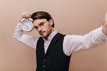 Serious young gentleman with brunette hair and bristle, wearing glasses, white shirt and black...