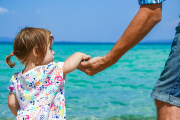 hands of happy parent and child at sea greece background