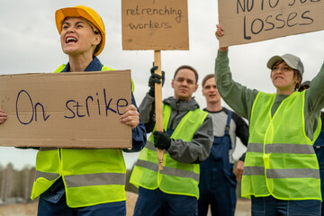 Group of employees in workwear carrying placards during strike at quarry
