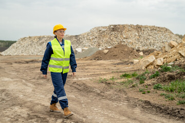 Confident female employer in workwear moving along construction site or quarry