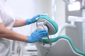 Dental assistant wipes the dental chair. Disinfection of dental equipment. Health care concept....