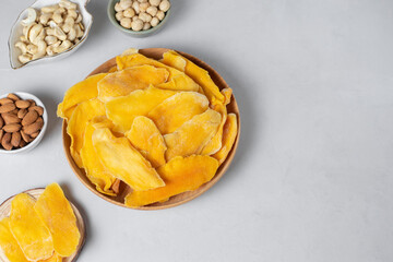 Wooden bowl dried mango fruit slices. Nuts: cashews, almonds, hazelnuts on light background. Concept natural organic healthy snack. Low sugars food- no candies. Sweets, norm of fats and oils