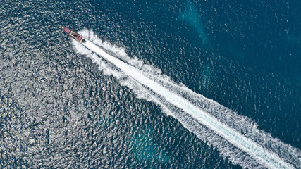 Aerial drone photo of small luxury speed boat cruising in deep blue waters of Mykonos island,...