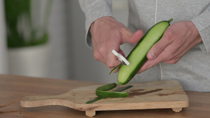 Close up of Man Peeling Cucumbers on Cutting Board