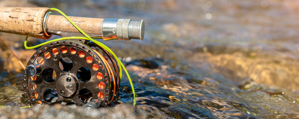 Close up fly fishing rod and reel on the river bank. Fishing scene on the banks.