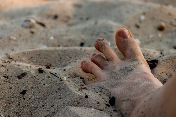 Woman's foot in the sand on a sandy beach.