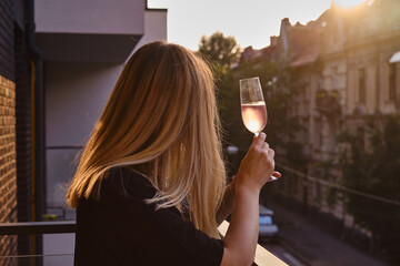 Girl with a glass of rose wine on the balcony. Drinks rose wine and enjoy the moment. A celebration...