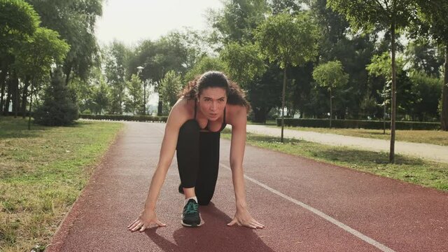 Athletic woman getting ready to start outdoor. Female runner prepare for jogging on track stadium. Sport motivation concept
