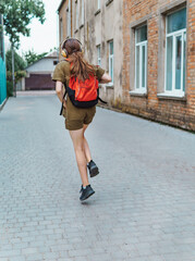 Obraz premium Teen schoolgirl on the way to the school. She is listening to music on headphones and holding a book. Education and back to school concept