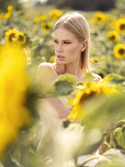 Fashion shooting on a field of sunflowers. Beautiful girl in a light linen dress. Environmentally friendly clothing. Healthy environment concept.