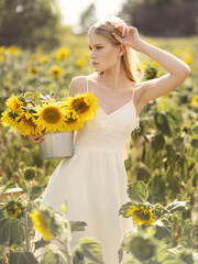 Fashion shooting on a field of sunflowers. Beautiful girl in a light linen dress. Environmentally friendly clothing. Healthy environment concept.