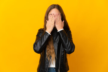 Child over isolated yellow background covering eyes by hands