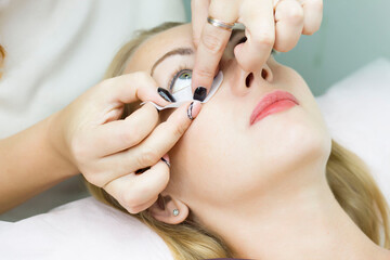 A young woman is glued a patch under her eyes, before the procedure of eyelash extension. Artificial extended eyelashes