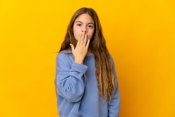 Child over isolated yellow background covering mouth with hand