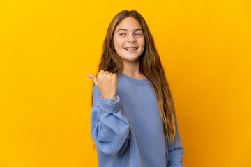 Child over isolated yellow background pointing to the side to present a product