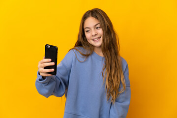 Child over isolated yellow background making a selfie