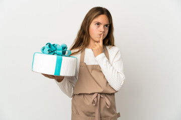 Little girl holding a big cake over isolated white background having doubts while looking up